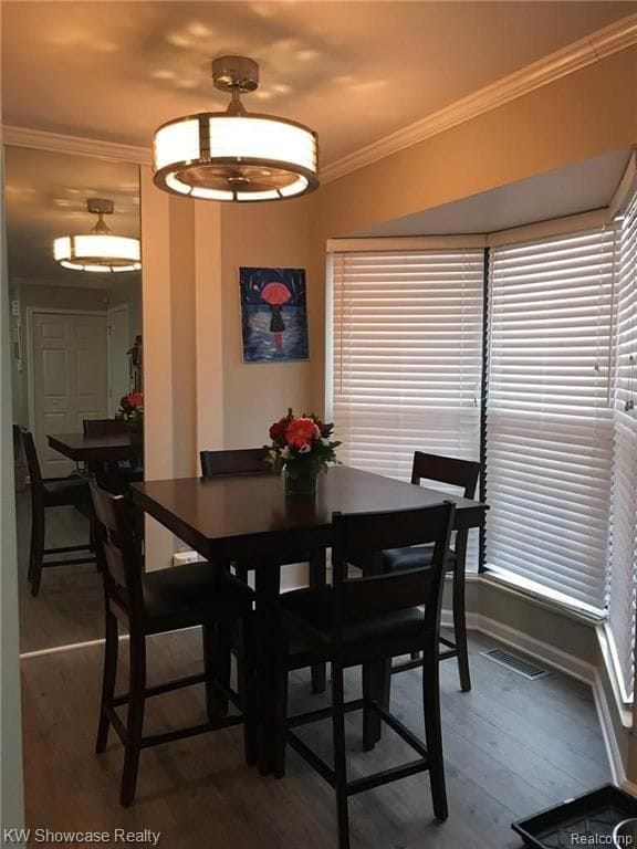 dining room featuring visible vents, crown molding, and wood finished floors