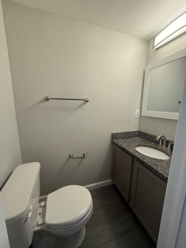 bathroom with toilet, baseboards, wood finished floors, and vanity