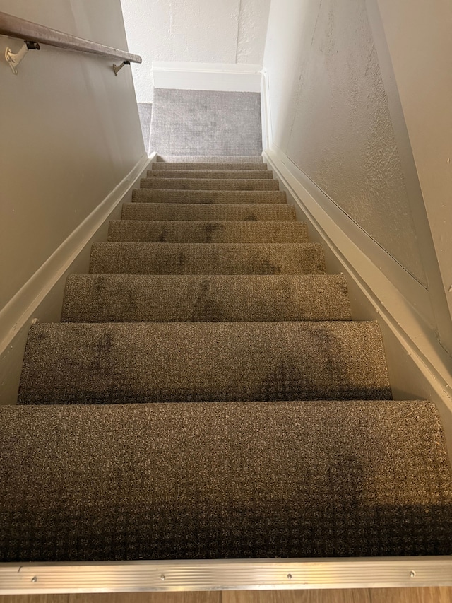 stairs featuring a textured wall and baseboards