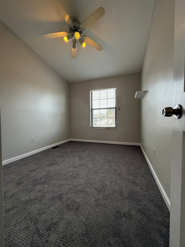 empty room featuring visible vents, a ceiling fan, vaulted ceiling, baseboards, and dark colored carpet