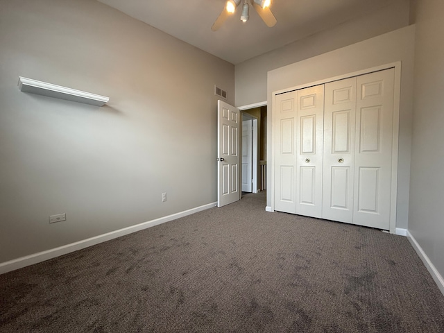 unfurnished bedroom featuring a closet, visible vents, dark carpet, ceiling fan, and baseboards