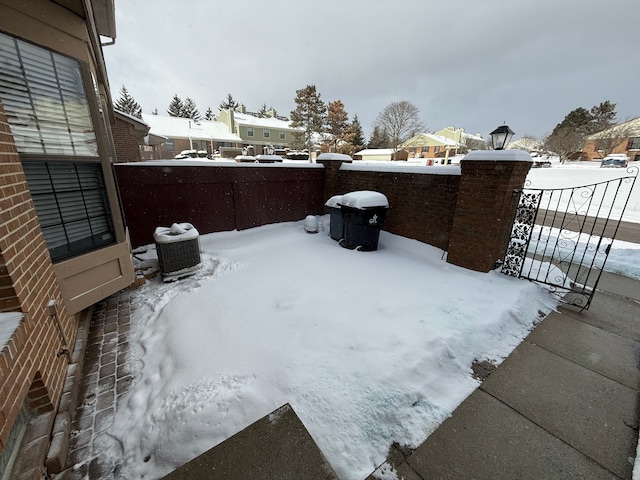 snowy yard with a gate, fence, and central AC