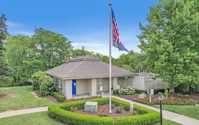 exterior space with roof with shingles, fence, and a front lawn