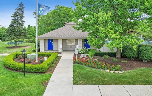 view of front of property featuring a front lawn and a shingled roof