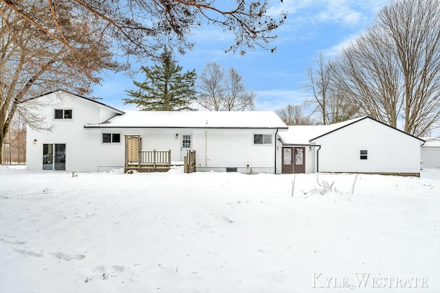 snow covered rear of property with a garage