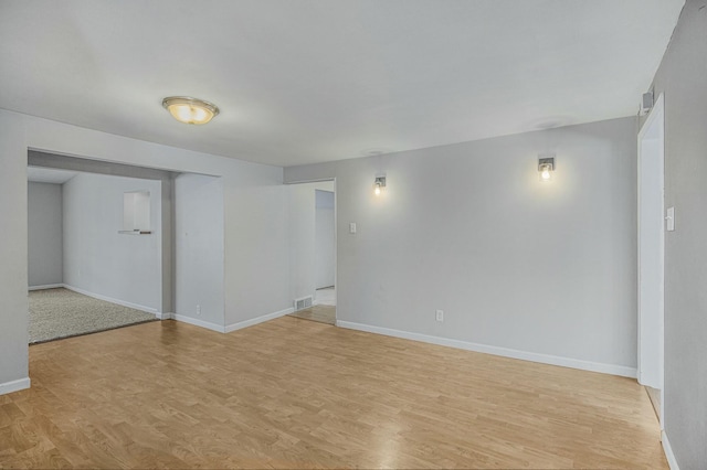 empty room with light wood-style floors, baseboards, and visible vents