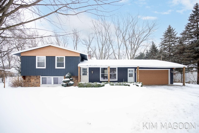 split level home featuring a garage and stone siding