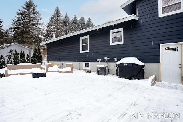 snow covered back of property featuring central air condition unit