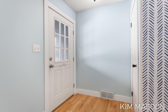 doorway to outside with light wood-style flooring, visible vents, and baseboards