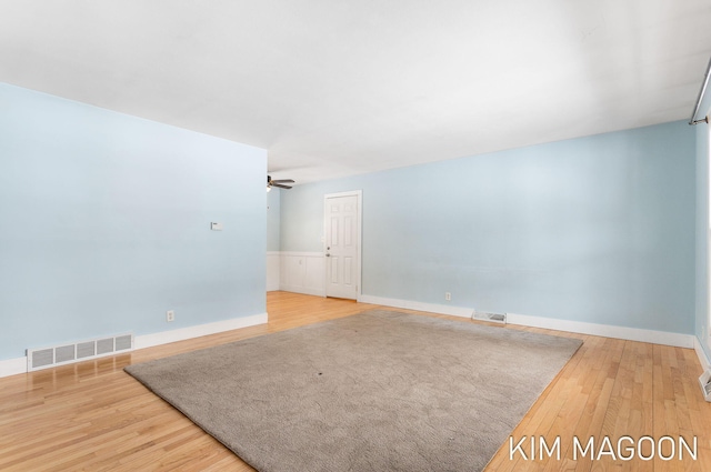 spare room with wood finished floors, visible vents, and a ceiling fan