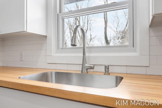 room details with wooden counters, white cabinetry, decorative backsplash, and a sink