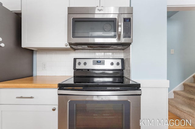 kitchen with wooden counters, appliances with stainless steel finishes, white cabinetry, and decorative backsplash