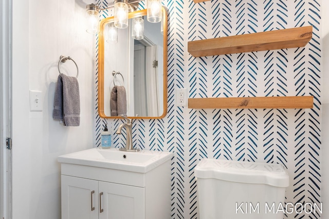 bathroom with vanity, toilet, and wallpapered walls