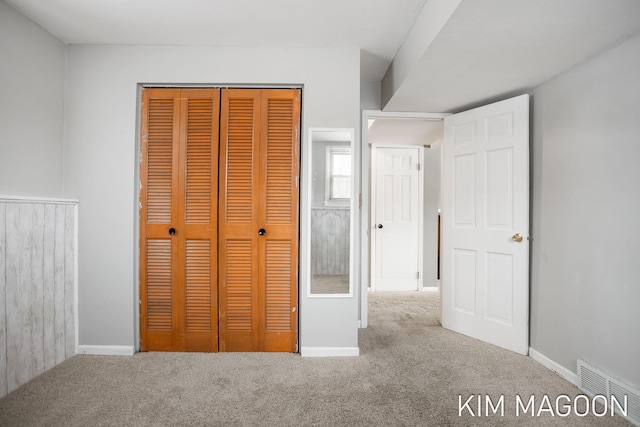 unfurnished bedroom with carpet floors, a closet, visible vents, and baseboards