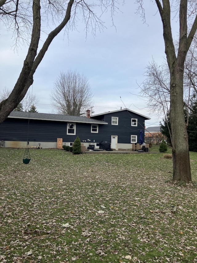 rear view of house featuring a lawn and a chimney