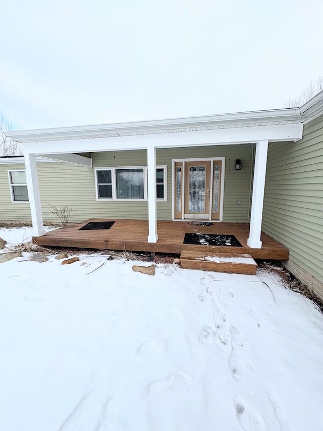 snow covered property entrance featuring a porch