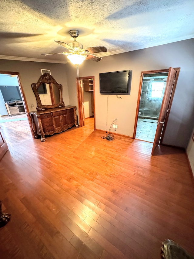 unfurnished living room with ceiling fan, a textured ceiling, crown molding, and wood finished floors