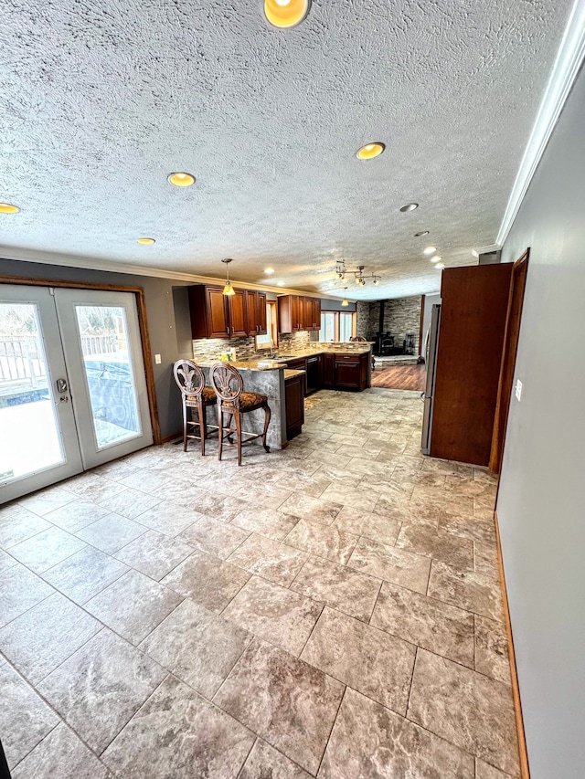 kitchen featuring tasteful backsplash, ornamental molding, open floor plan, light countertops, and a kitchen bar