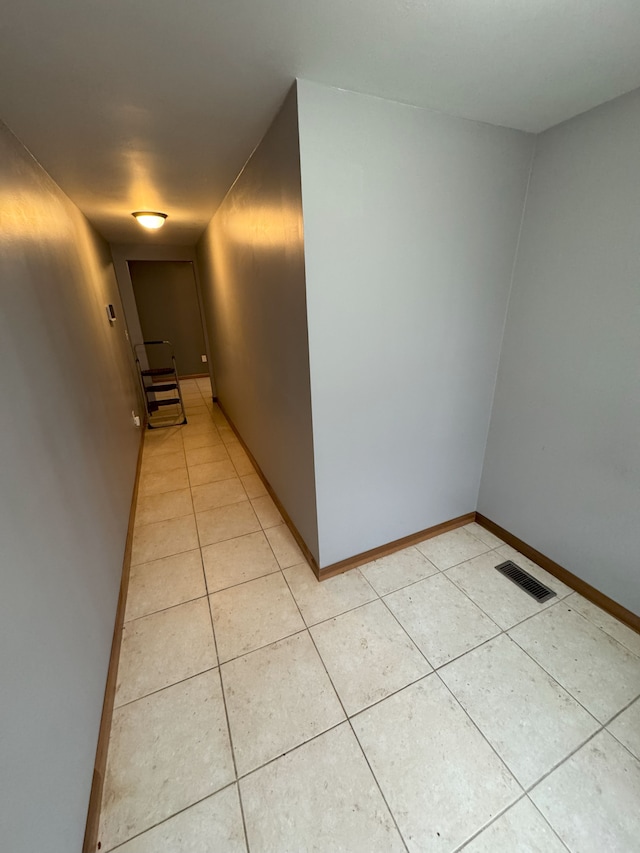 corridor with light tile patterned floors, visible vents, and baseboards