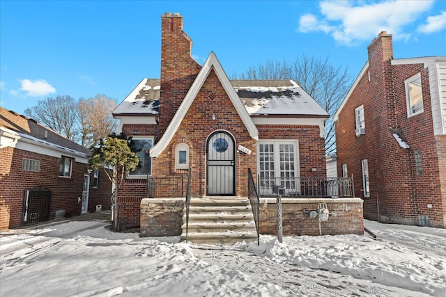 tudor home featuring brick siding and a chimney