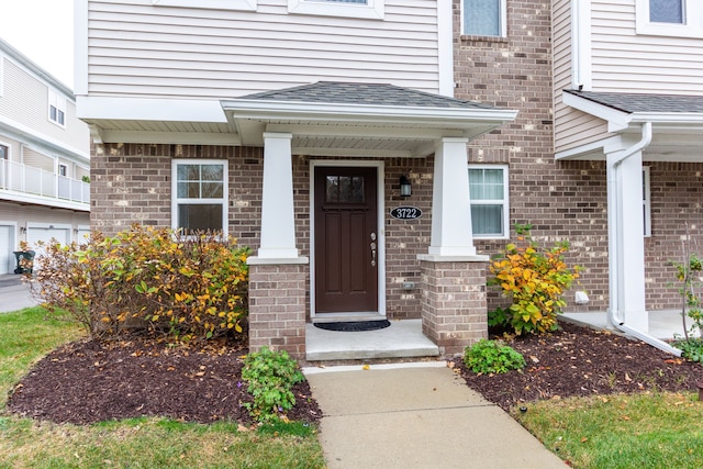 property entrance featuring brick siding and roof with shingles