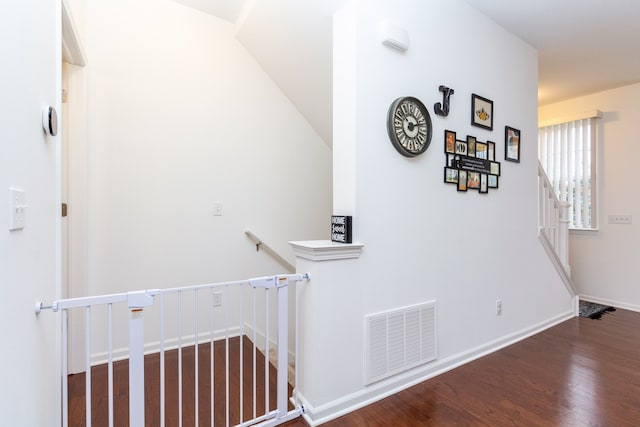 hall with dark wood-style flooring, visible vents, and baseboards