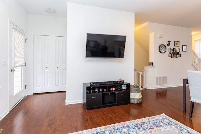 living area featuring stairs, dark wood-style flooring, visible vents, and baseboards