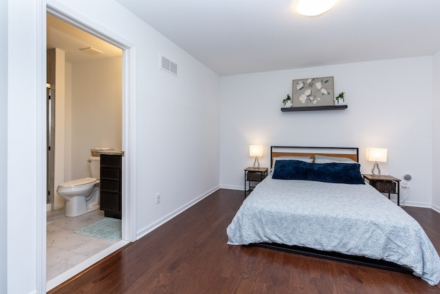 bedroom with ensuite bathroom, wood finished floors, visible vents, and baseboards