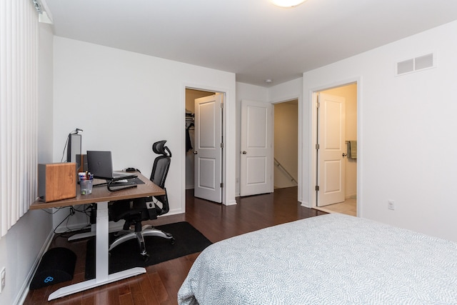 bedroom with baseboards, a spacious closet, visible vents, and dark wood finished floors