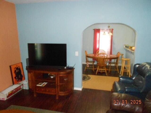 living area featuring arched walkways and dark wood-type flooring