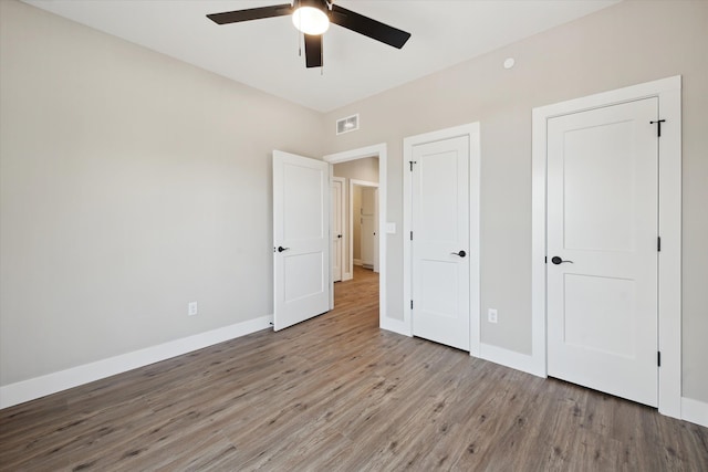 unfurnished bedroom featuring a ceiling fan, light wood-type flooring, visible vents, and baseboards