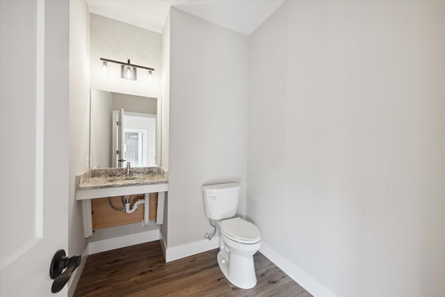 half bath featuring baseboards, toilet, and wood finished floors