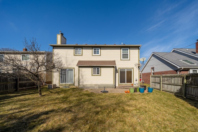 rear view of property featuring a lawn, a chimney, and a fenced backyard