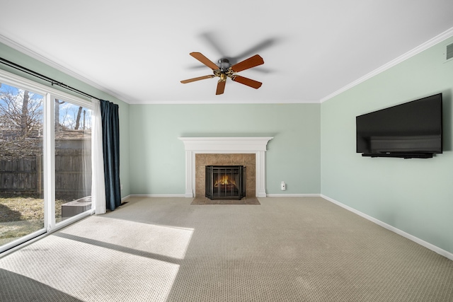 unfurnished living room with a tile fireplace, carpet, baseboards, and ornamental molding