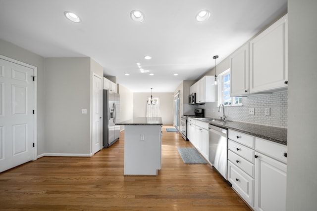 kitchen featuring backsplash, white cabinetry, appliances with stainless steel finishes, and a kitchen island