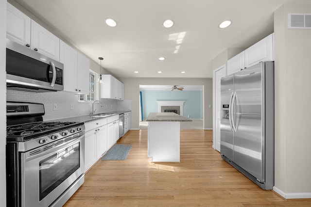 kitchen featuring visible vents, a sink, appliances with stainless steel finishes, white cabinetry, and backsplash