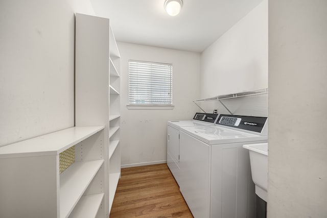 washroom featuring washer and dryer, laundry area, baseboards, and light wood-type flooring