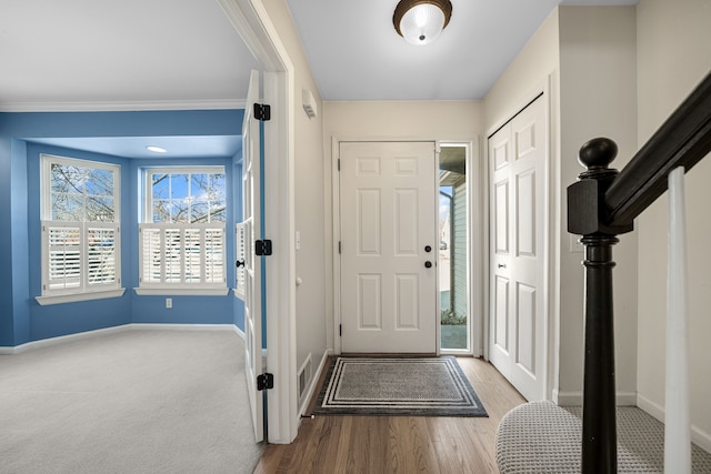 foyer entrance featuring visible vents, stairs, baseboards, and wood finished floors