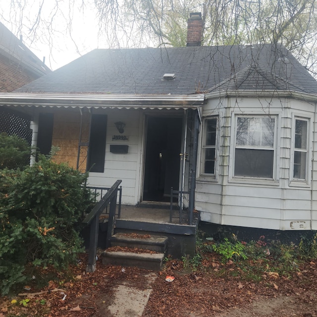 view of exterior entry featuring a porch and a chimney