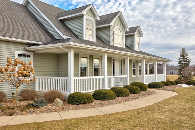 view of side of property with covered porch and roof with shingles