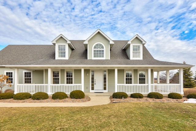 view of front of house with covered porch, roof with shingles, and a front lawn