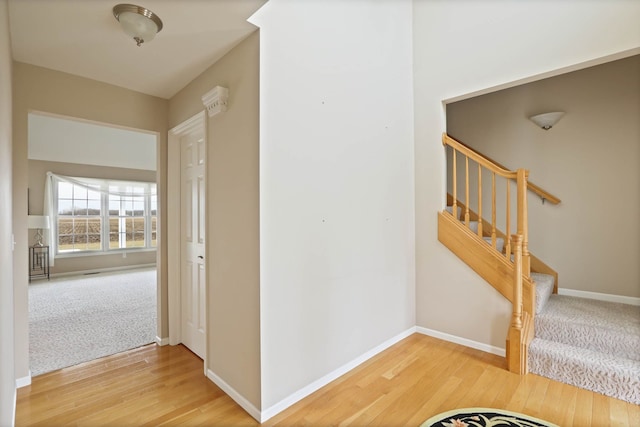 hallway with stairs, baseboards, and wood finished floors