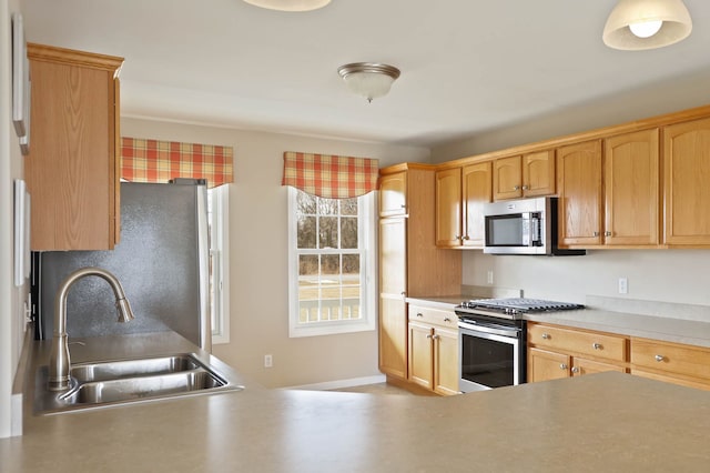 kitchen featuring stainless steel appliances, a sink, and light countertops