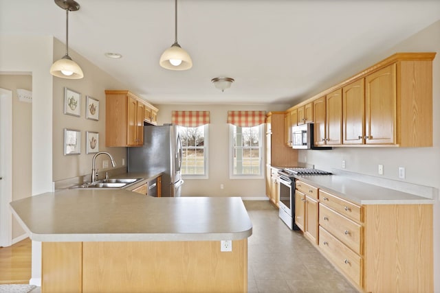 kitchen featuring a peninsula, stainless steel appliances, light countertops, light brown cabinets, and a sink