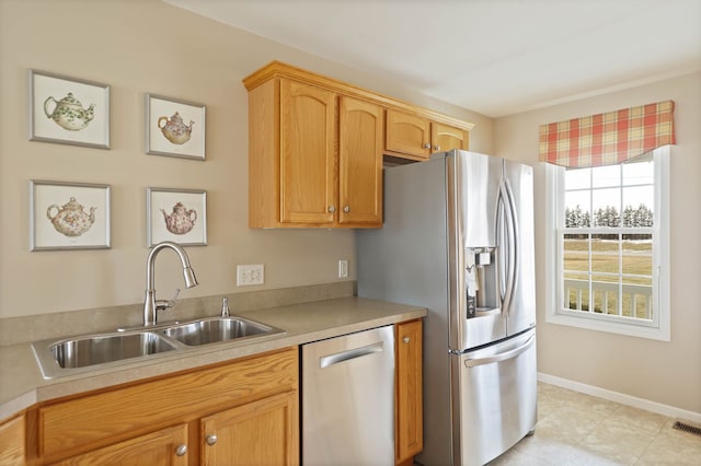 kitchen featuring baseboards, appliances with stainless steel finishes, light countertops, and a sink