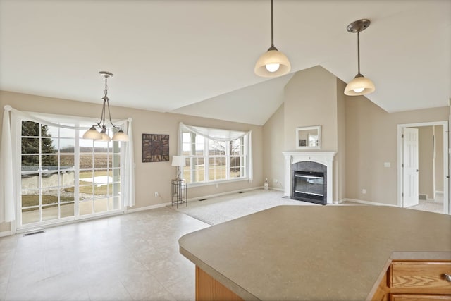 kitchen featuring visible vents, baseboards, open floor plan, pendant lighting, and a high end fireplace