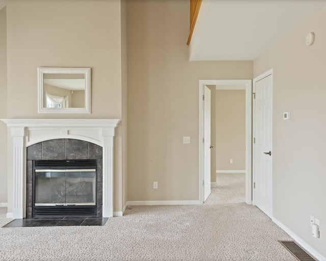 unfurnished living room featuring carpet, visible vents, baseboards, and a tile fireplace