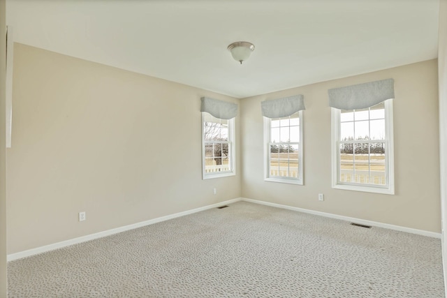 carpeted spare room featuring visible vents and baseboards