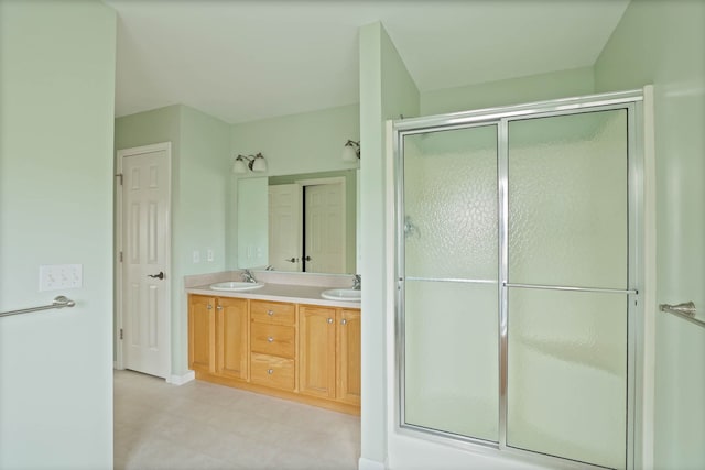 bathroom featuring a stall shower, tile patterned floors, a sink, and double vanity