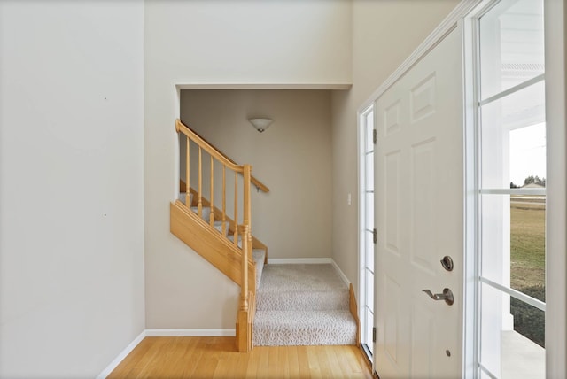 foyer with stairs, light wood finished floors, and baseboards